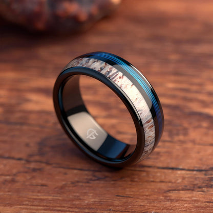 Domed black tungsten ring with blue fishing line and brown-patterned pale deer antler in separate grooves