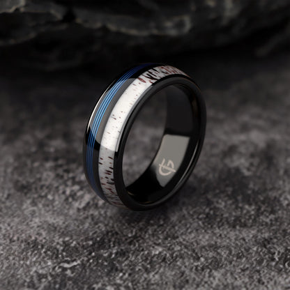 Domed black tungsten ring with blue fishing line and brown-patterned pale deer antler in separate grooves