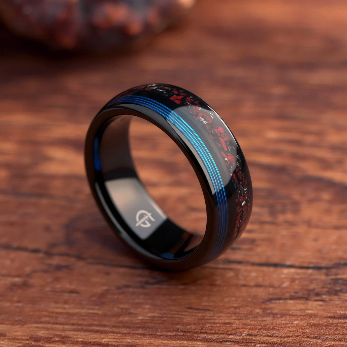 Polished black tungsten ring with fine blue fishing line beside red dinosaur bone and silver-gray meteorite fragments
