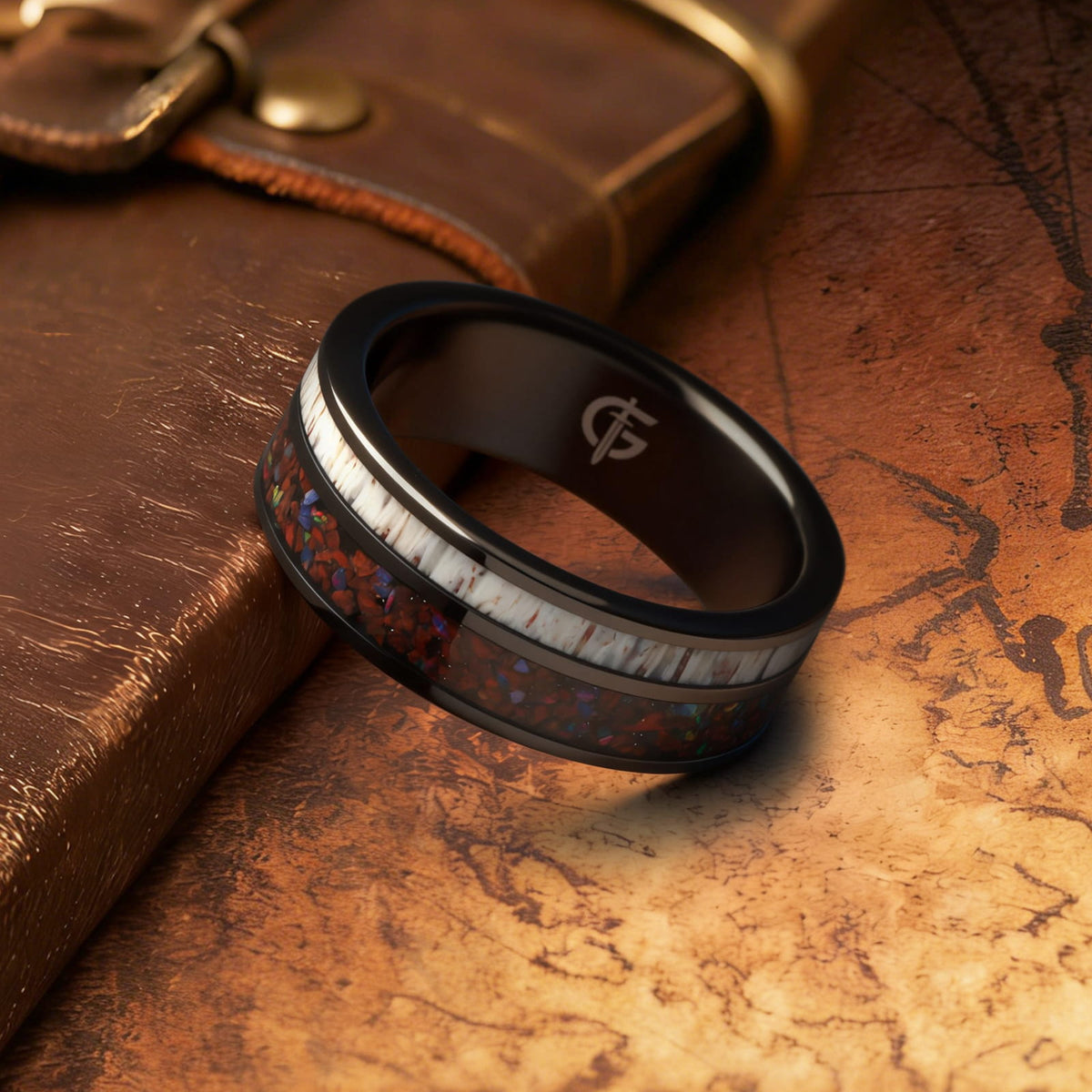 Polished black tungsten ring with pale deer antler beside red dinosaur bone and multicolored natural opal
