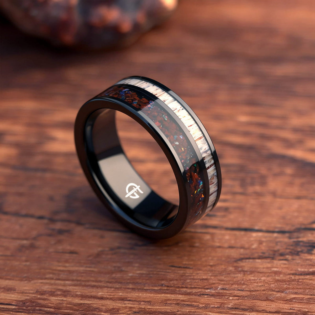Polished black tungsten ring with pale deer antler beside red dinosaur bone and multicolored natural opal