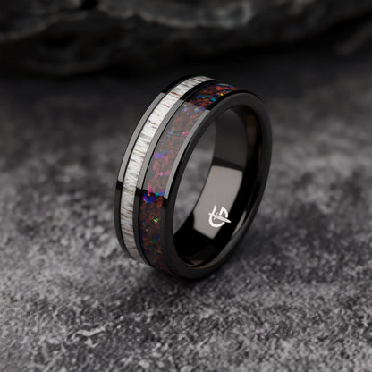 Polished black tungsten ring with pale deer antler beside red dinosaur bone and multicolored natural opal