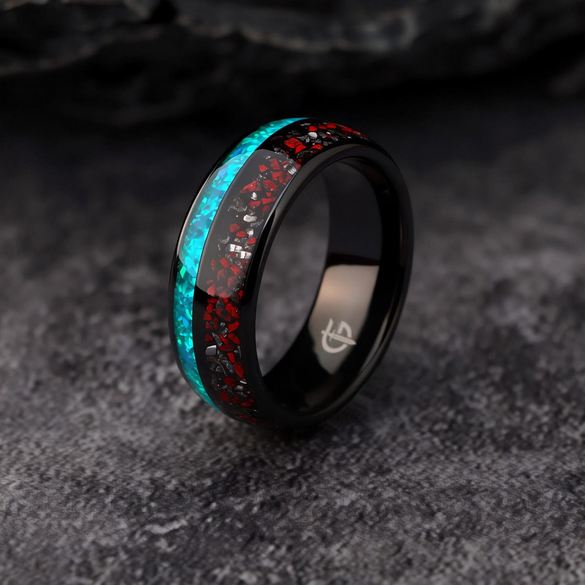 Black domed tungsten ring with red and silver-gray fragments beside a blue-green opal inlay.