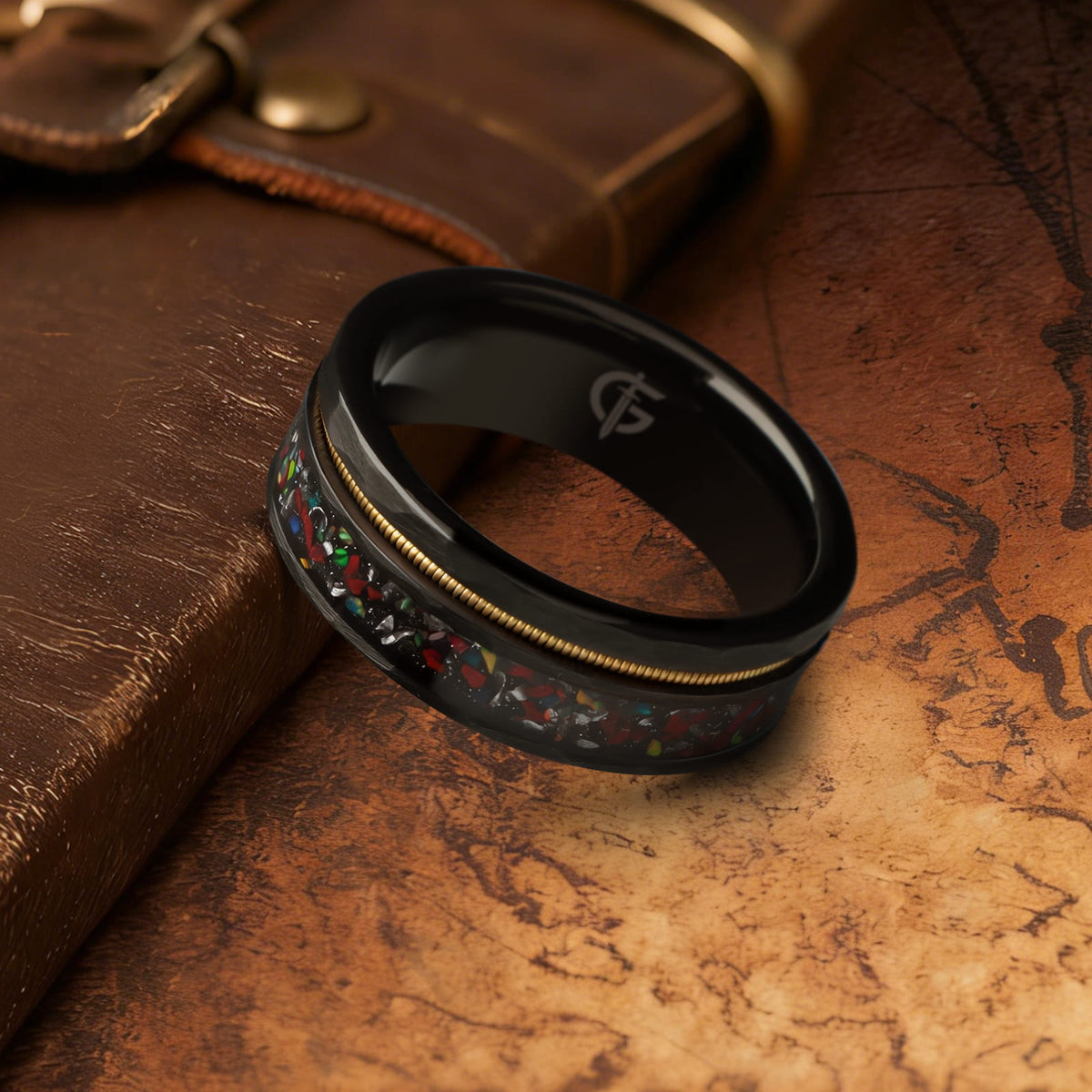 Hammered black tungsten carbide ring with a gold-tone guitar string and red-brown, silver-gray and multicolor inlays