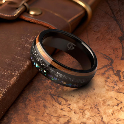 Black domed ring with brown wood, silver-gray meteorite, and iridescent abalone in three separate channels.