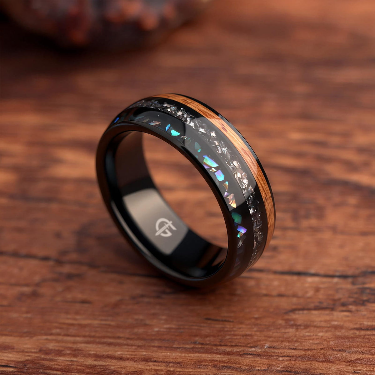 Black domed ring with brown wood, silver-gray meteorite, and iridescent abalone in three separate channels.