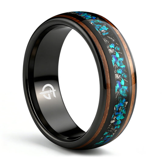 Black domed ring with two wood strips framing a center inlay of silver-gray and blue-green fragments.