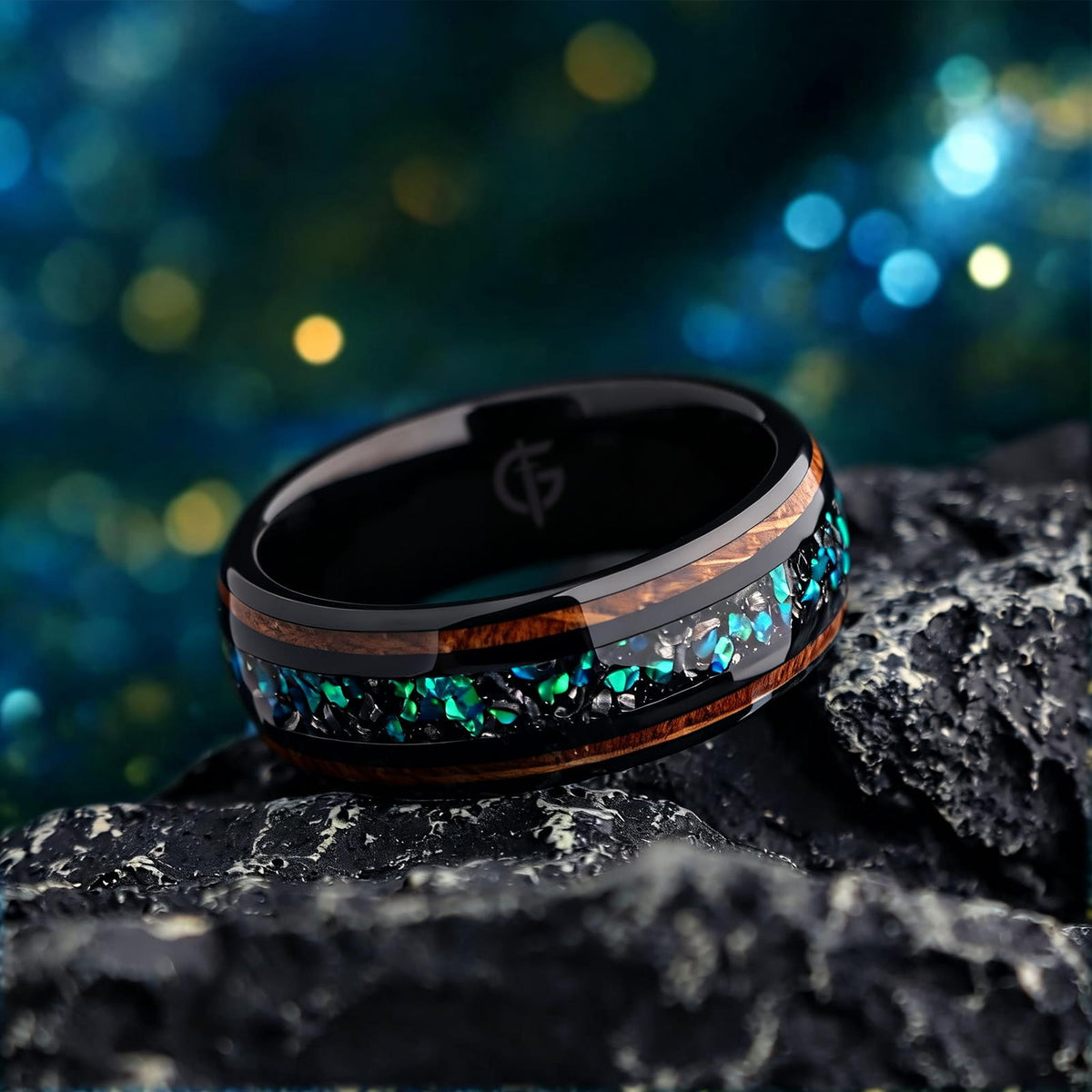 Black domed ring with two wood strips framing a center inlay of silver-gray and blue-green fragments.