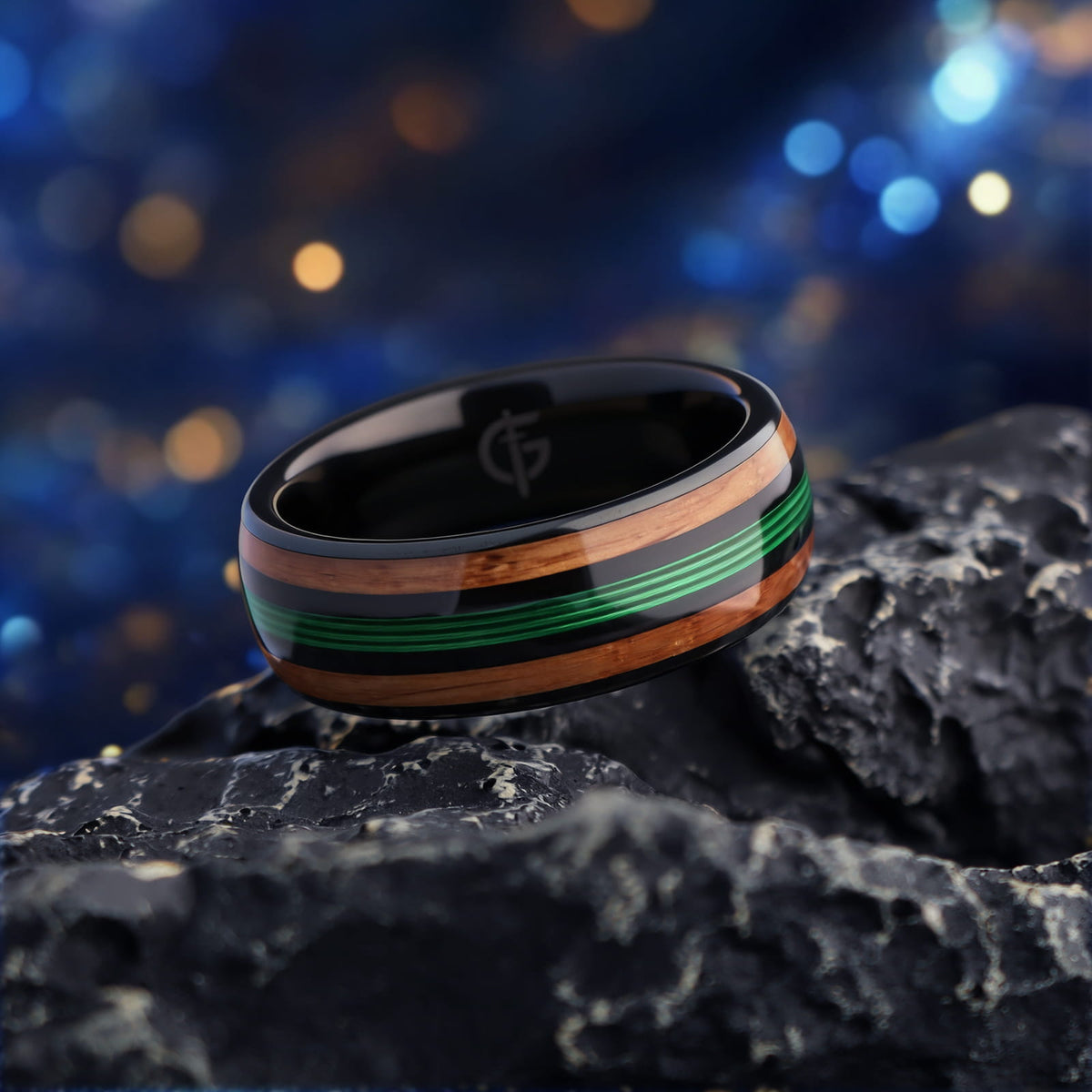Polished black tungsten ring with green fishing line between two brown whiskey barrel wood bands