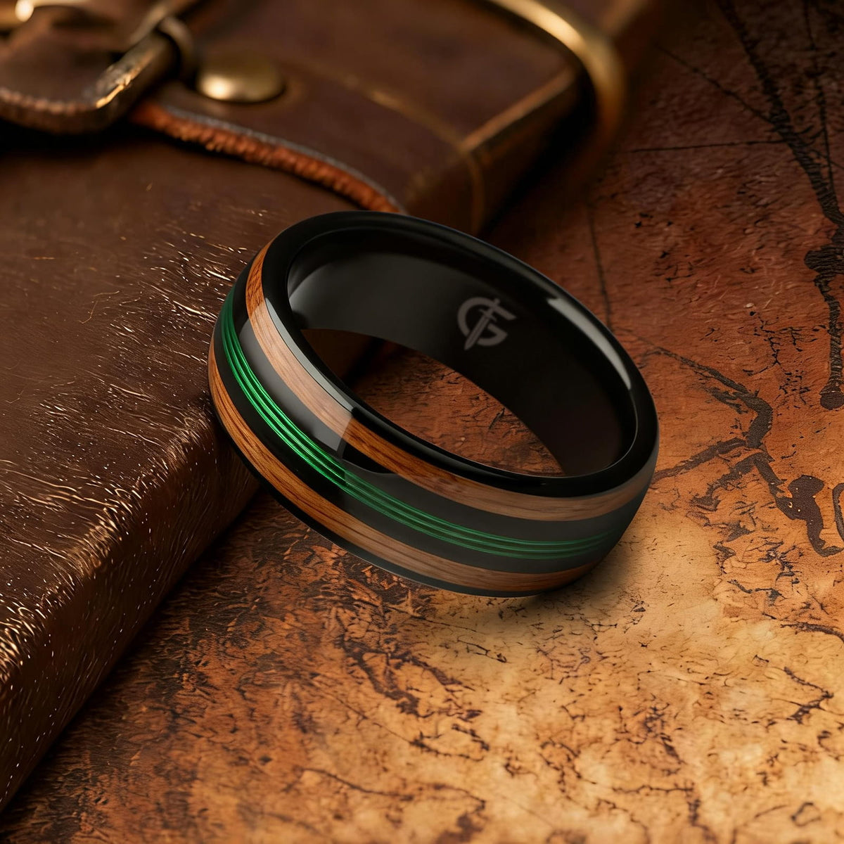 Polished black tungsten ring with green fishing line between two brown whiskey barrel wood bands