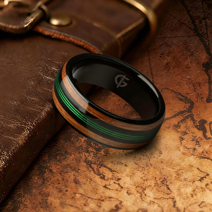 Polished black tungsten ring with green fishing line between two brown whiskey barrel wood bands