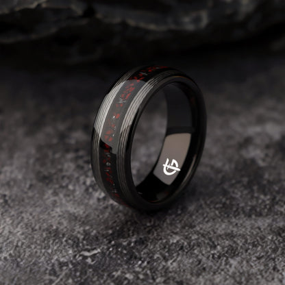 Black tungsten ring with silver-tone fishing line flanking a red dinosaur bone and silver-gray meteorite center