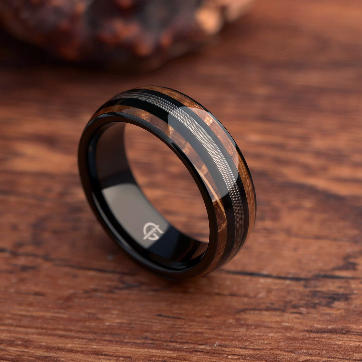 Black tungsten ring with silver-tone fishing line centered between two whiskey barrel wood bands